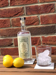 Narez Organic Vodka 70cl bottle with lemons and ice-filled glass on wooden table against brick wall.