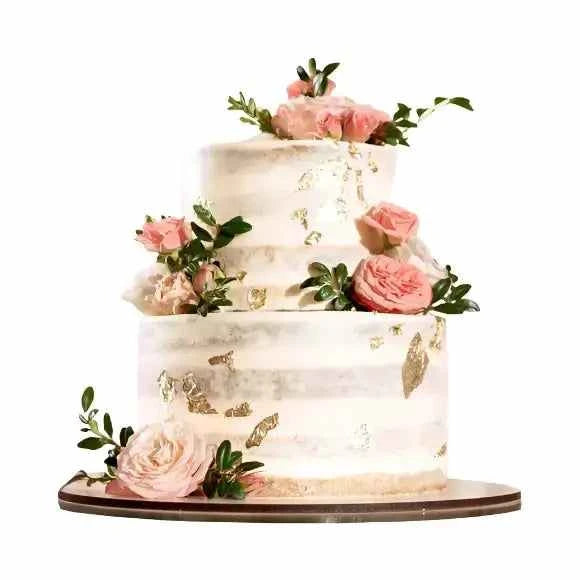 Three-tiered Fairy Dream Wedding Cake with delicate flowers and gold accents on a wooden cake stand.
