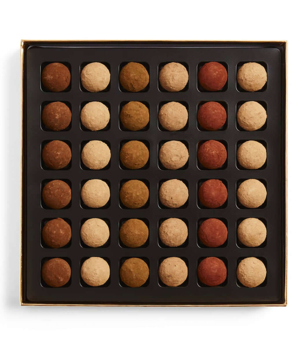 Box of assorted chocolate truffles in a grid pattern on a white background