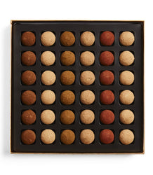 Box of assorted chocolate truffles in a grid pattern on a white background