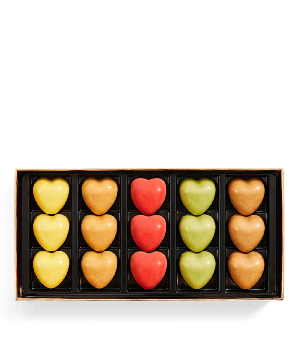 Box of heart-shaped chocolates in various colors on a white background