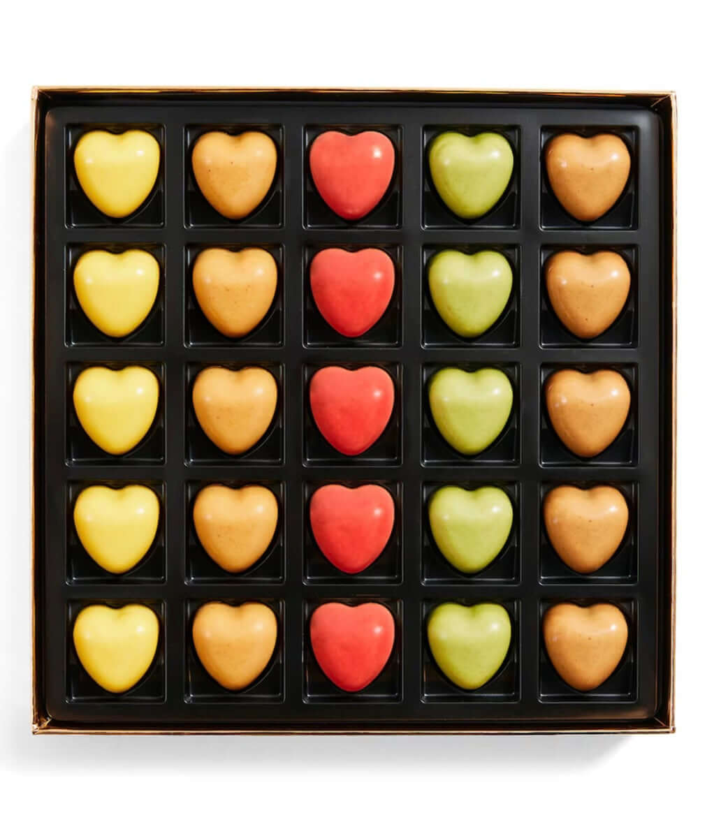 Box of heart-shaped chocolates in various colors on a white background