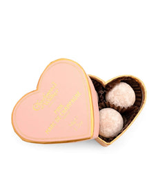 Heart-shaped pink box with gold text containing two white truffles on a white background