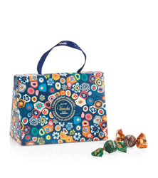 Colorful floral-patterned chocolate box with 'Vенchi' branding, accompanied by some chocolates on a white background.