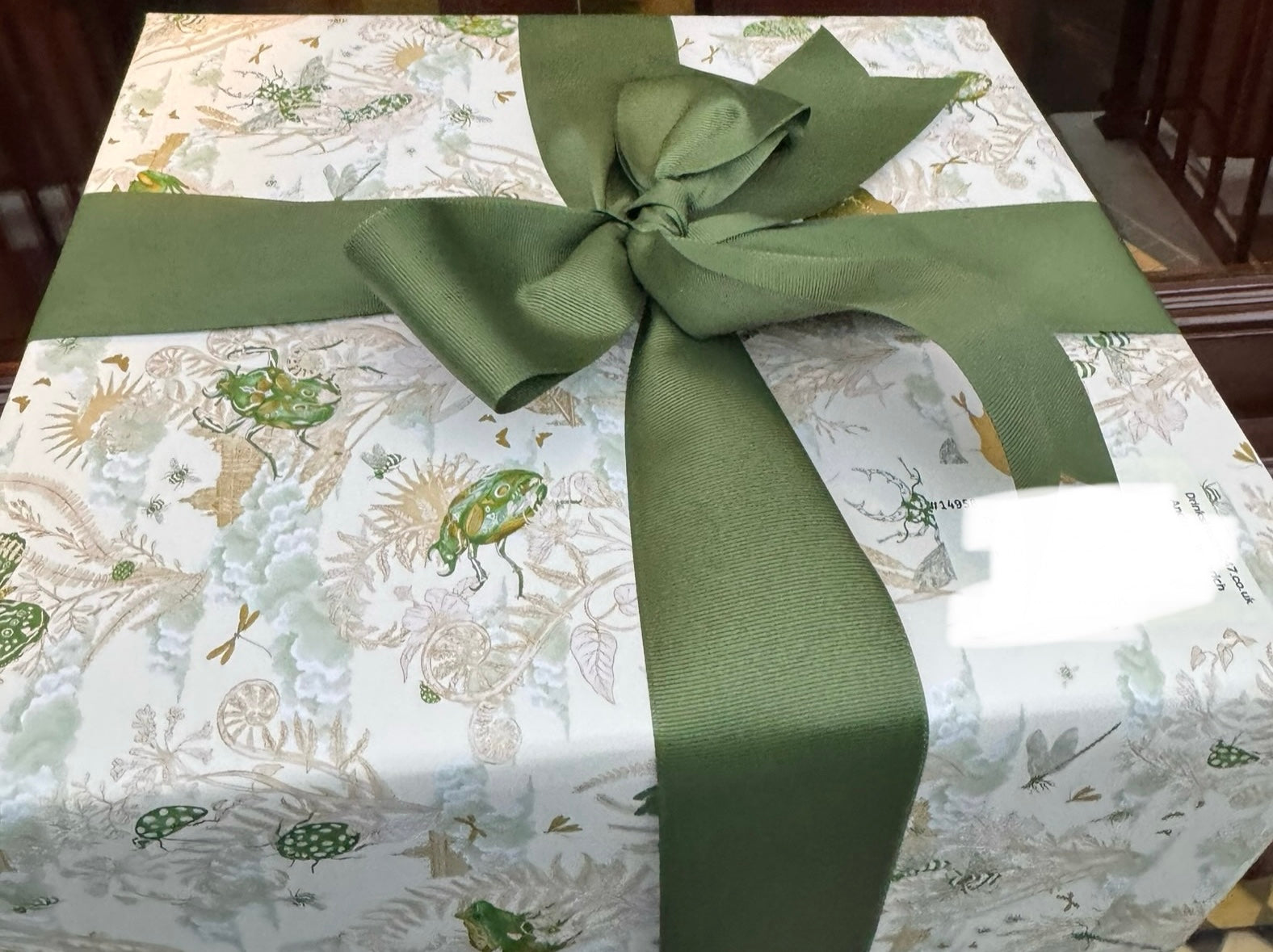 Gift wrapped in patterned paper with a green ribbon on a table.