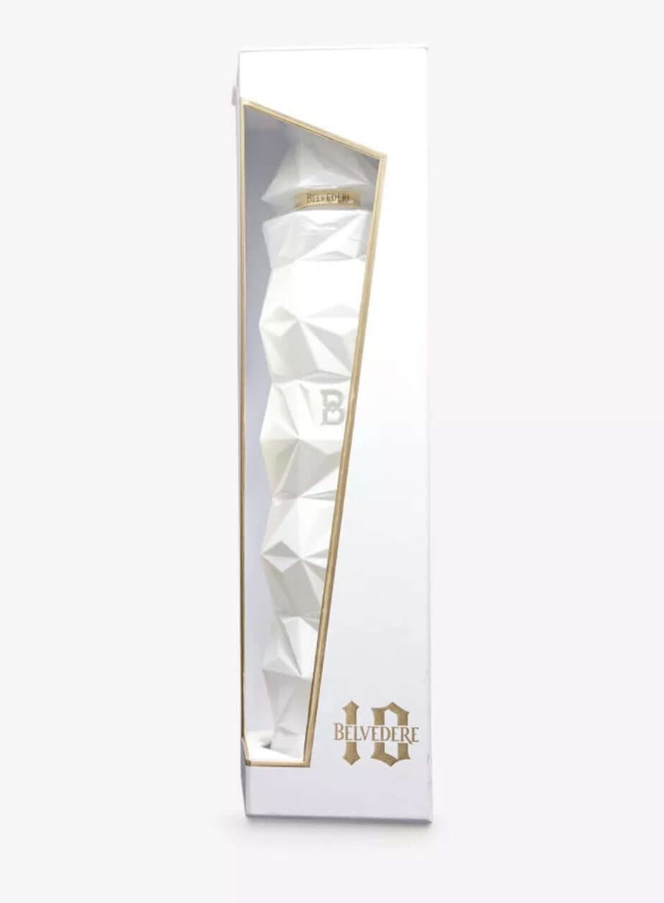 Tall, narrow white gift box with a gold-trimmed window displaying the ultra-premium Belvedere 10 vodka bottle. The bottle has a striking faceted, geometric, crystalline white glass design resembling a faceted diamond or modern sculpture, with embossed 