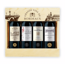 Wooden gift crate containing four 75cl Bordeaux red wine bottles neatly arranged in a row, presented as a premium Bordeaux wine gift pack. The light natural wood box has a hinged lid (open) with burnt-in branding: "GRANDS VINS DE BORDEAUX