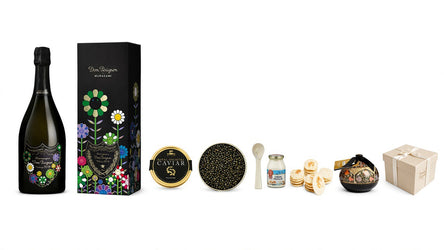 A luxury gourmet gift hamper featuring a bottle of Dom Pérignon Non-Alcoholic Champagne, a floral black gift box, a tin of caviar, a bowl of caviar, a small jar, crackers, a decorative bowl, and a beige gift box, arranged on a plain white background.