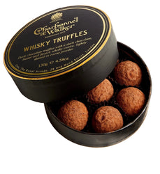 A round black gift box of Charbonnel & Walker Whisky Truffles, with the lid leaning against the open base to reveal five chocolate truffles inside. The lid features gold lettering and a gold crest on a black background.