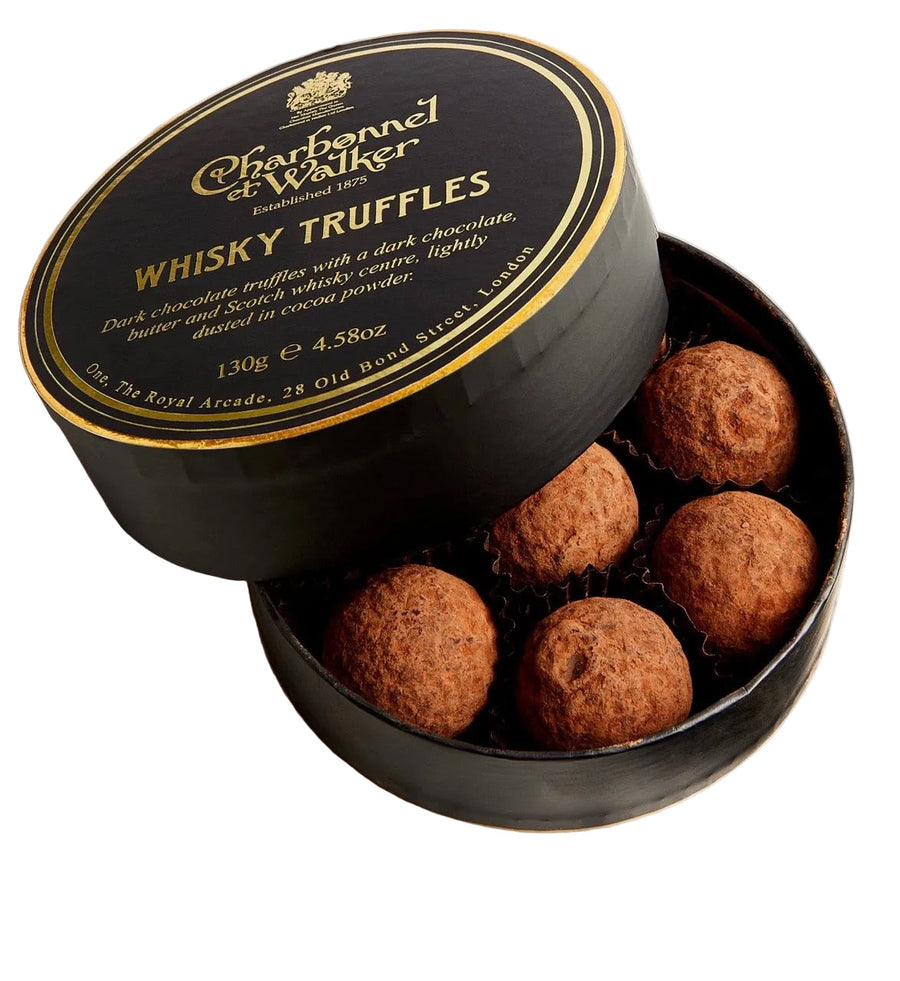 A round black gift box of Charbonnel & Walker Whisky Truffles, with the lid leaning against the open base to reveal five chocolate truffles inside. The lid features gold lettering and a gold crest on a black background.