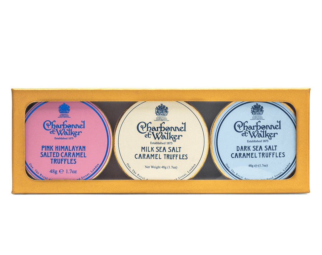 Three Charbonnel et Walker truffle boxes in pink, white, and blue on a gold tray.