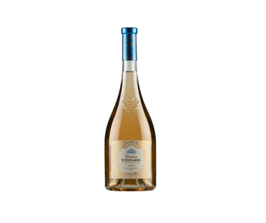 Pale salmon-pink bottle of Château d'Esclans Côtes de Provence Rosé 2022 (75cl), featuring a clear glass with elegant pale rosé wine inside. The label is cream-colored with intricate gold-embossed borders and heraldic crest at the top, reading "Château d'Esclans" in classic script, "Côtes de Provence" below, and "2022" prominently displayed. The bottle has a striking metallic blue foil capsule on the neck.