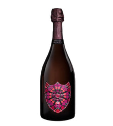 A bottle of Dom Pérignon Grand Cru Blanc de Blancs 2010 champagne with a distinctive pink and orange mandala patterned label, set against a plain white background.