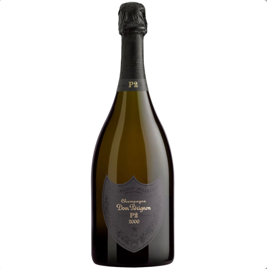 A bottle of Dom Pérignon Plénitude 2 P2 Vintage 2000 champagne presented in a premium gift box. The distinctive black and silver label marks this rare second release of the legendary 2000 vintage, signifying extended maturation.