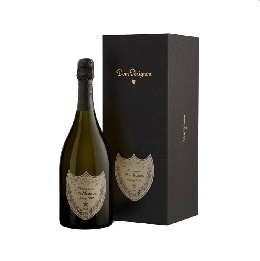 Dom Pérignon Vintage 2012 Champagne 75cl bottle displayed beside its elegant black gift box with gold “Dom Pérignon” scripting and subtle shield emblem, featuring the bottle’s classic green glass, black foil top, and ornate gold shield label with “Champagne Dom Pérignon Vintage 2012 Brut” inscription and vine motifs.