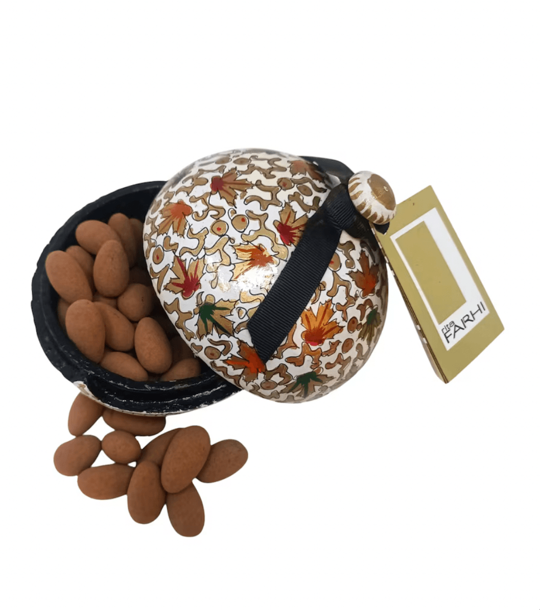 Decorative container with patterned lid and almonds on a white background