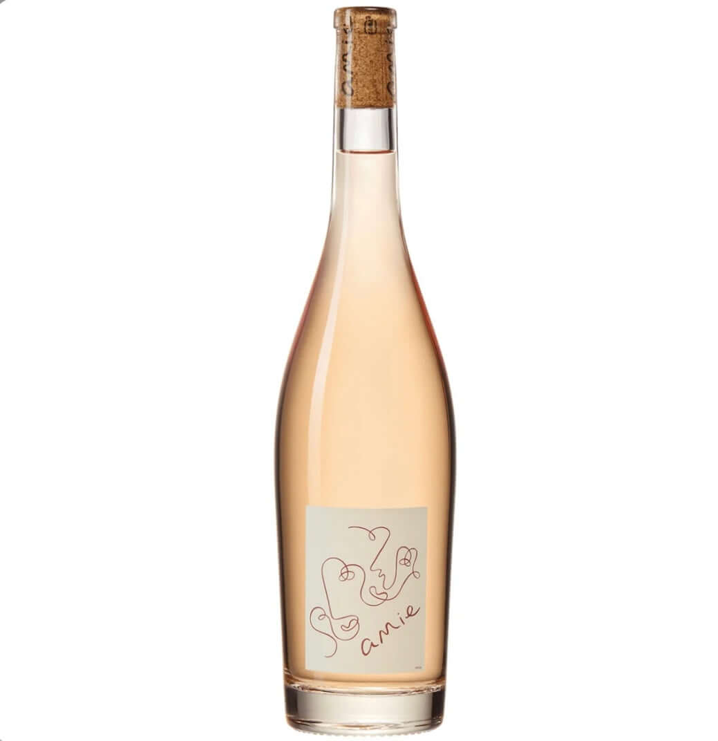 Pale salmon-pink bottle of Amie Rosé 75cl, a dry Grenache rosé from Southern France. The elegant, clear glass bottle has a natural cork closure with a branded top and a minimalist cream-colored label featuring delicate, abstract line-drawn faces forming a heart shape, with the word 