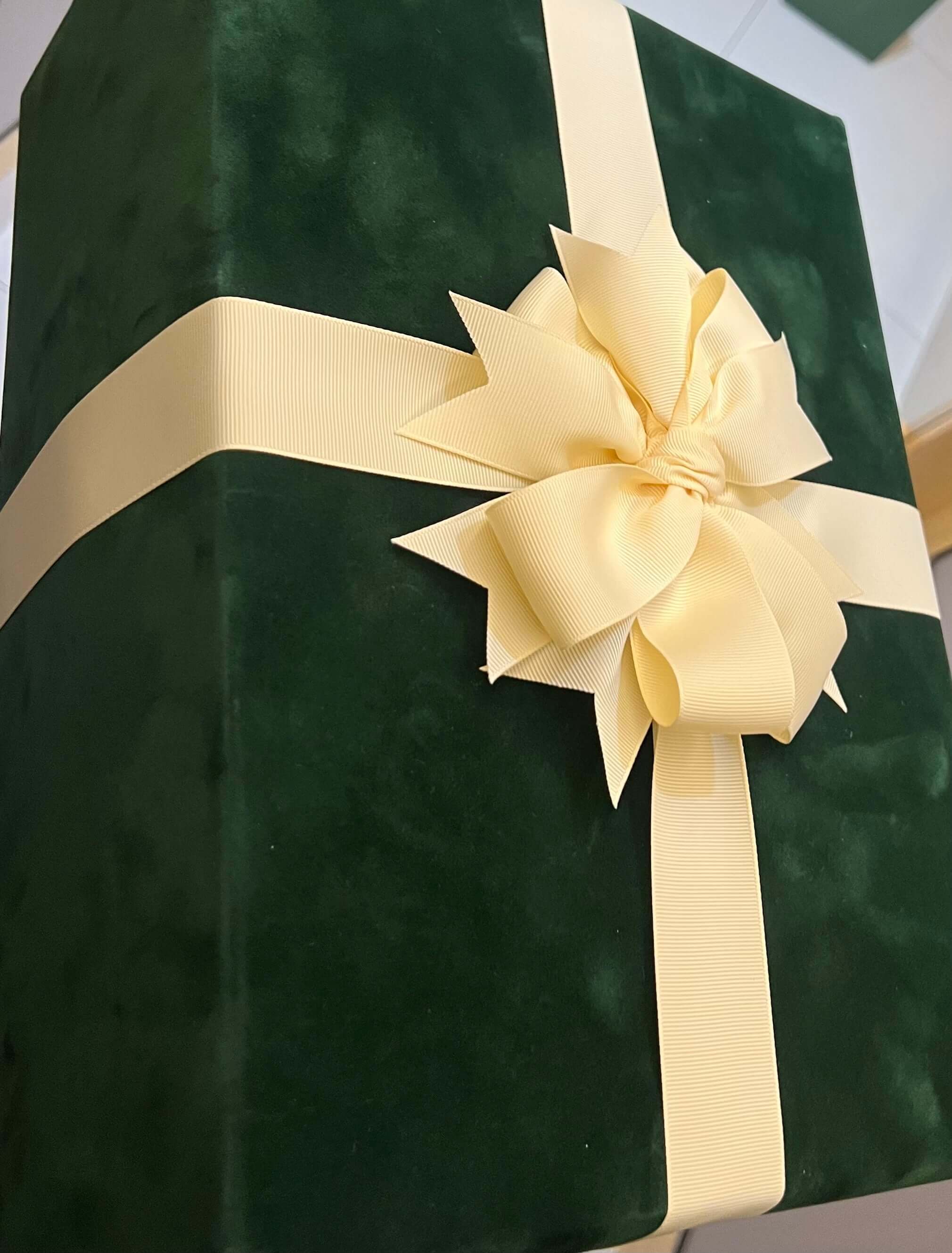 Green velvet gift box with a large beige bow