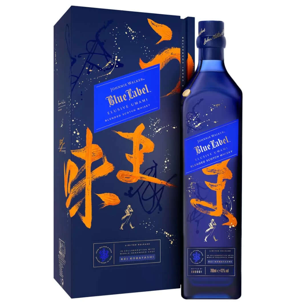 Luxury presentation gift box and bottle of Johnnie Walker Blue Label Elusive Umami blended Scotch whisky. The tall navy-blue box features bold, expressive orange Japanese calligraphy-style brushstrokes spelling "味" (umami) in large, artistic strokes, with abstract splashes and dynamic lines in orange and white.