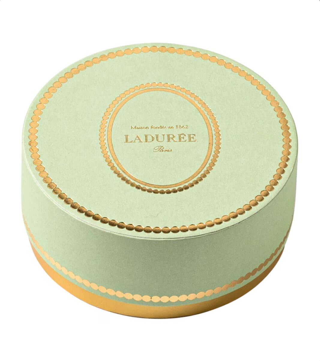 Round green box with gold trim and 'Ladurée' branding on a white background