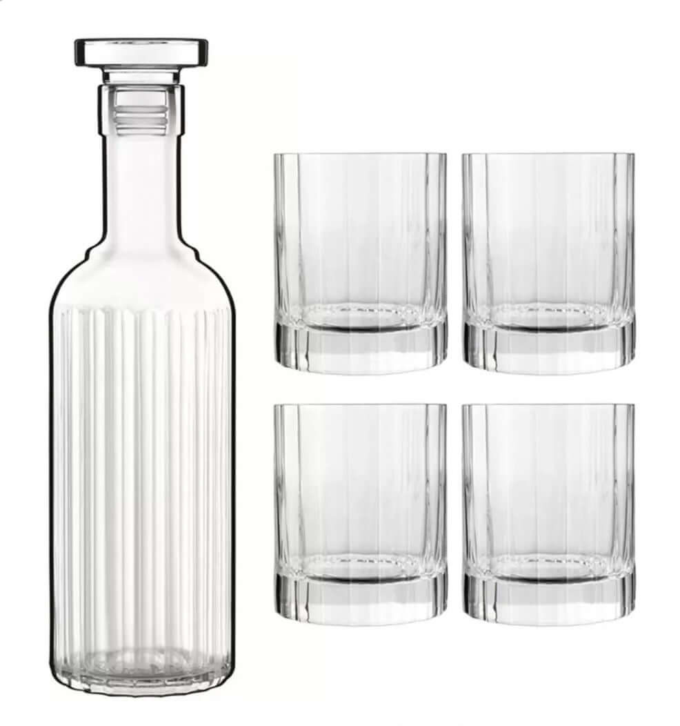 A clear ribbed glass decanter with a stopper next to four matching clear ribbed glass tumblers on a white background.