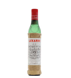 A bottle of Luxardo Gentile di Luxardo liqueur, featuring a green glass bottle with a red cap and a beige paper-wrapped neck and base, set against a plain white background.