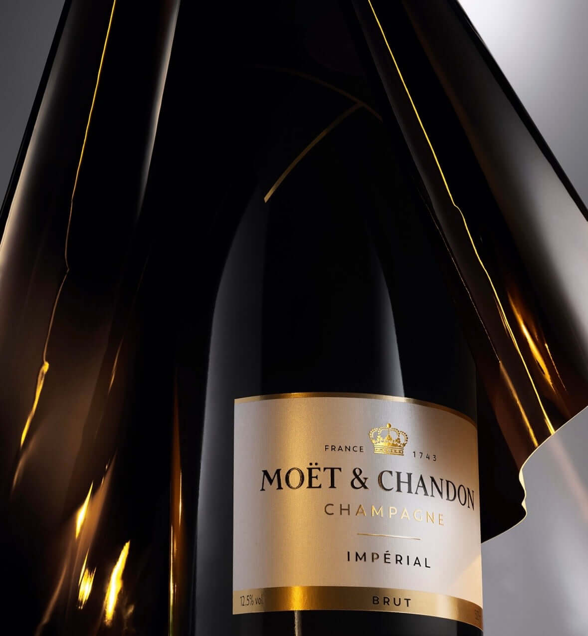 A close-up of a Moët & Chandon Impérial Brut champagne bottle with a reflective black glass body and a cream label with gold accents.