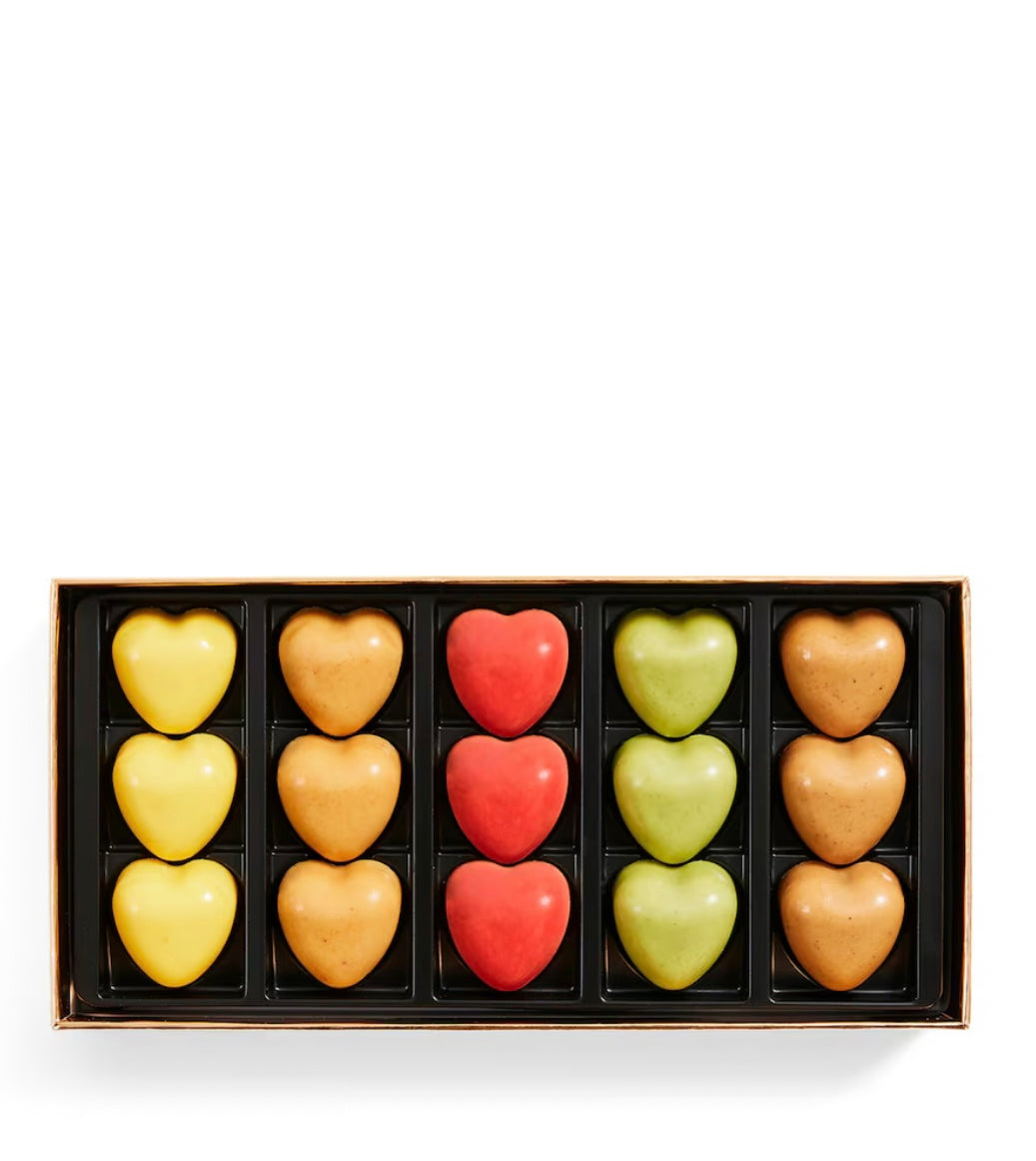 Box of heart-shaped chocolates in various colors on a white background