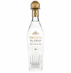 Clear glass bottle of Patrón El Cielo four-times distilled luxury blanco tequila with a distinctive tall, elegant shape featuring vertical etched lines at the base resembling agave leaves or crystal facets. The bottle contains crystal-clear liquid and has a prominent gold foil capsule with intricate embossed bee and floral motifs.