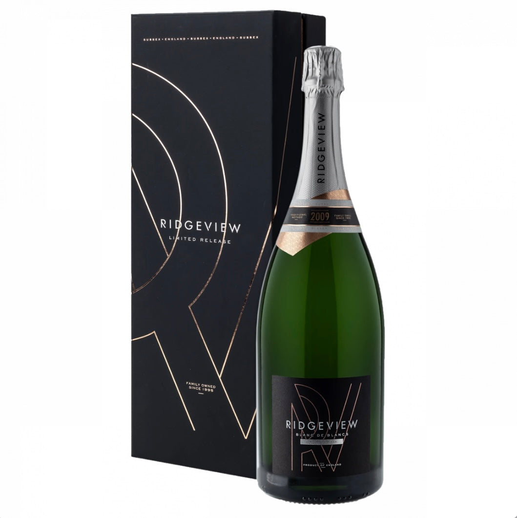 Matte black gift box and large green magnum bottle (150cl) of Ridgeview Blanc de Blancs Limited Release 2009 English sparkling wine. The tall black presentation box features elegant rose-gold geometric line artwork forming an abstract "R" motif, repeated "SUSSEX • ENGLAND" text in gold at the top, "RIDGVIEW LIMITED RELEASE" in white, and "FAMILY OWNED SINCE 1995" in small gold lettering at the base. The bottle has a silver foil capsule, a copper-toned vintage band with "2009" highlighted, and a black label 