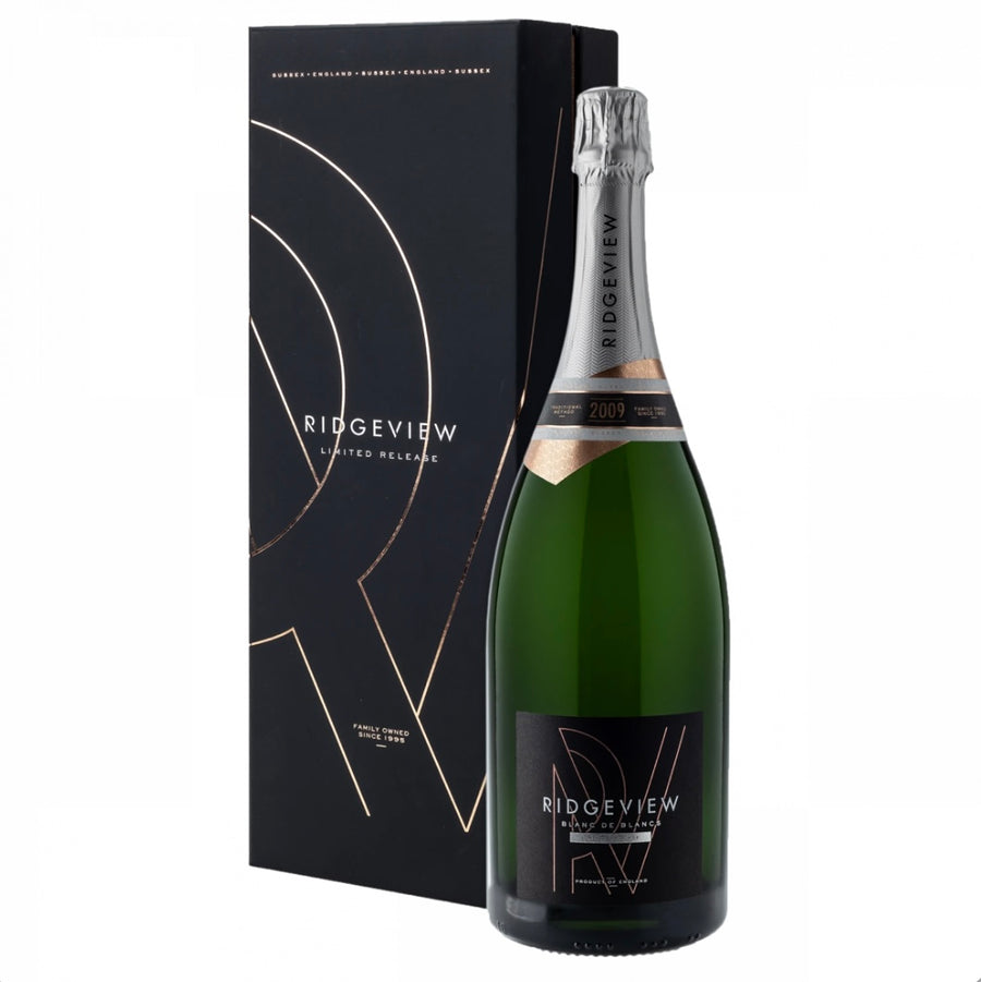 Matte black gift box and large green magnum bottle (150cl) of Ridgeview Blanc de Blancs Limited Release 2009 English sparkling wine. The tall black presentation box features elegant rose-gold geometric line artwork forming an abstract "R" motif, repeated "SUSSEX • ENGLAND" text in gold at the top, "RIDGVIEW LIMITED RELEASE" in white, and "FAMILY OWNED SINCE 1995" in small gold lettering at the base. The bottle has a silver foil capsule, a copper-toned vintage band with "2009" highlighted, and a black label 