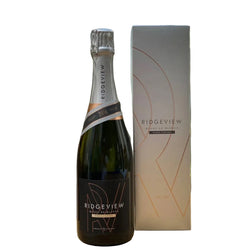 Dark green bottle of Ridgeview Blanc de Blancs Single Vineyard 2016 English sparkling wine (75cl), with a silver foil capsule and black label featuring rose-gold geometric "RV" monogram design, "RIDGEVIEW", "BLANC DE BLANCS", "SINGLE VINEYARD", and "2016" vintage band in copper and black. Displayed next to its tall matte silver-grey gift box with subtle orange geometric line artwork and "RIDGEVIEW BLANC DE BLANCS SINGLE VINEYARD" text in black.