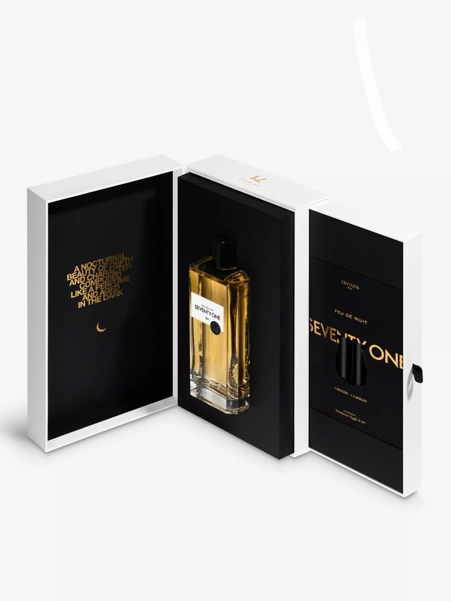 Perfume bottle in an open white and black box with gold accents on a white background