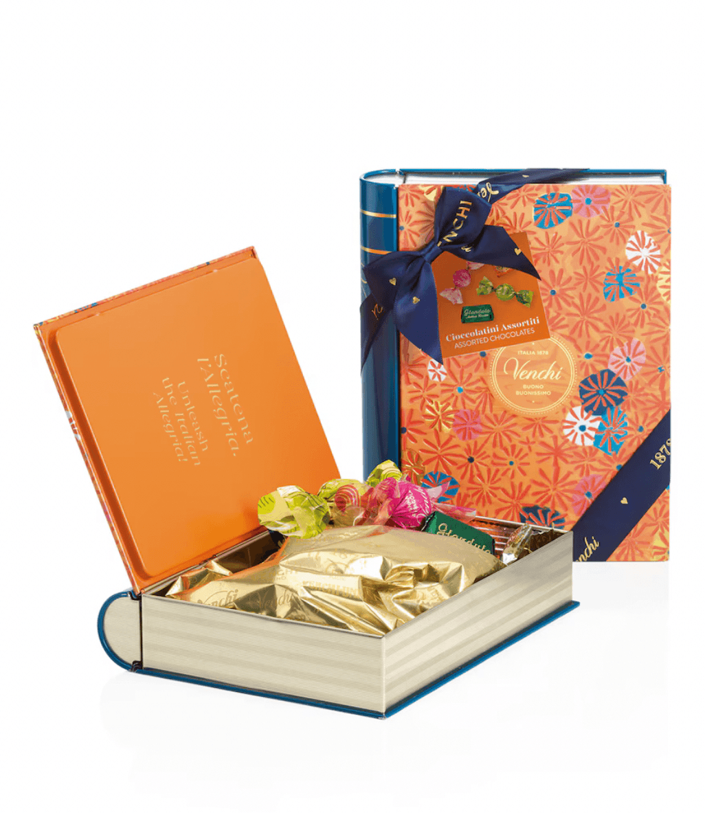 Book-shaped gift box with gold-wrapped chocolates and a colorful Nandlal box on a white background