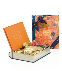 Book-shaped gift box with gold-wrapped chocolates and a colorful Nandlal box on a white background