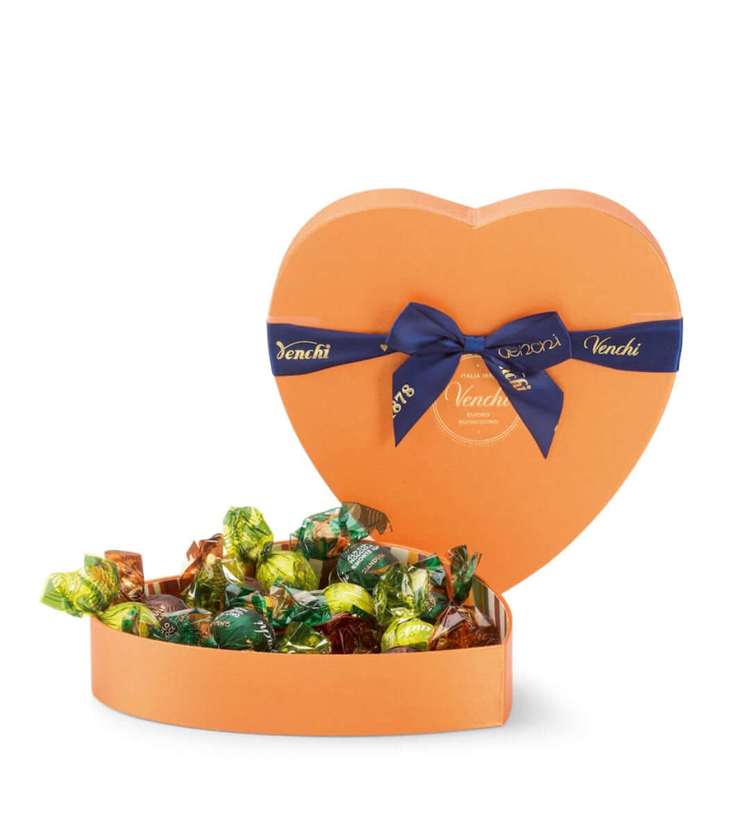 Heart-shaped chocolate box filled with candies and a blue ribbon, on a white background