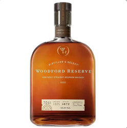 Amber glass bottle of Woodford Reserve Distiller's Select Kentucky Straight Bourbon Whiskey with a distinctive rounded, barrel-like shape and warm copper-brown liquid. The bottle features a dark gray foil capsule with embossed text, a prominent label with "WOODFORD RESERVE" in elegant uppercase gold lettering, "DISTILLER'S SELECT" arched above, and "KENTUCKY STRAIGHT BOURBON WHISKEY" below. 
