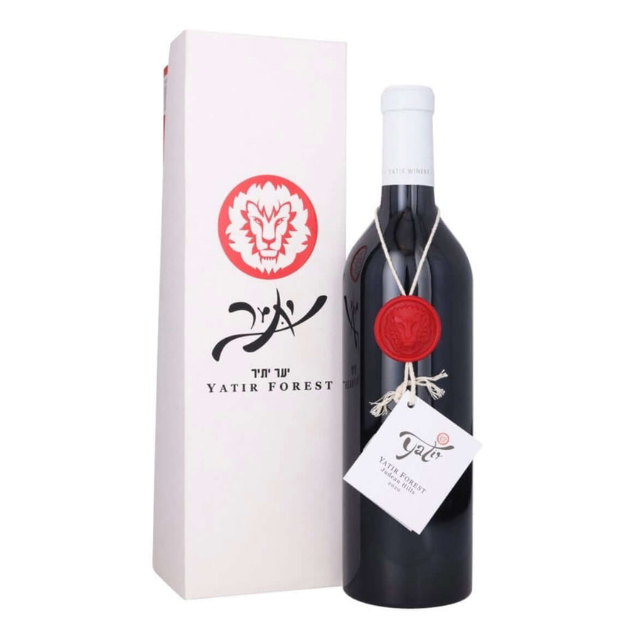 A bottle of Yatir Forest wine next to its tall white gift box. The bottle is dark glass with a white capsule, sealed with a red wax seal, and has a white hangtag.